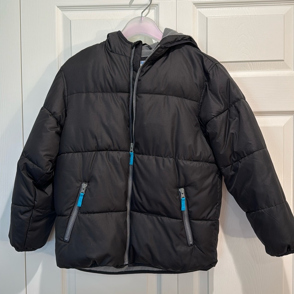 Puffer jacket. Black with grey fleece lining, blue zipper pulls. Attached hood.